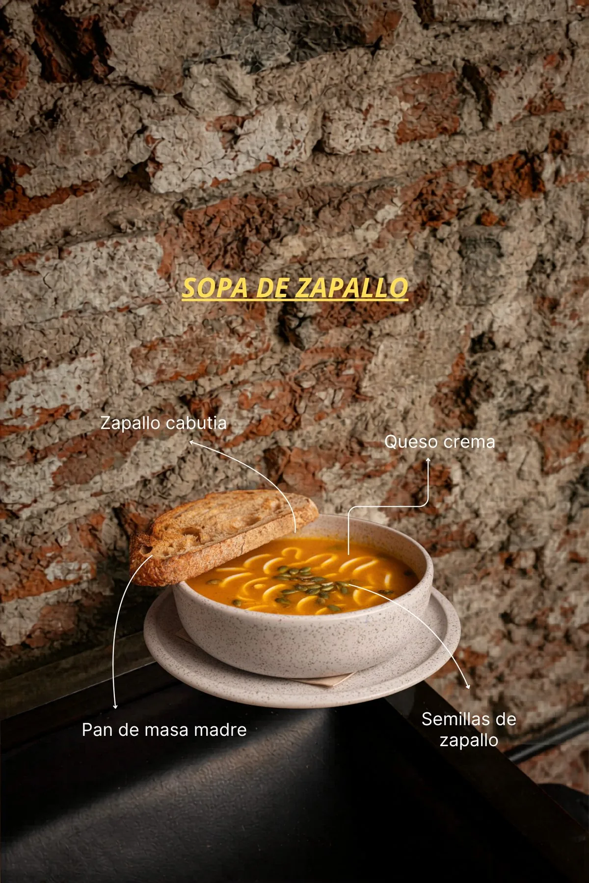 Sopa de zapallo cabutia con queso crema, semillas de zapallo y pan de masa madre, servida en bowl de cerámica en SĀNTAL Buenos Aires