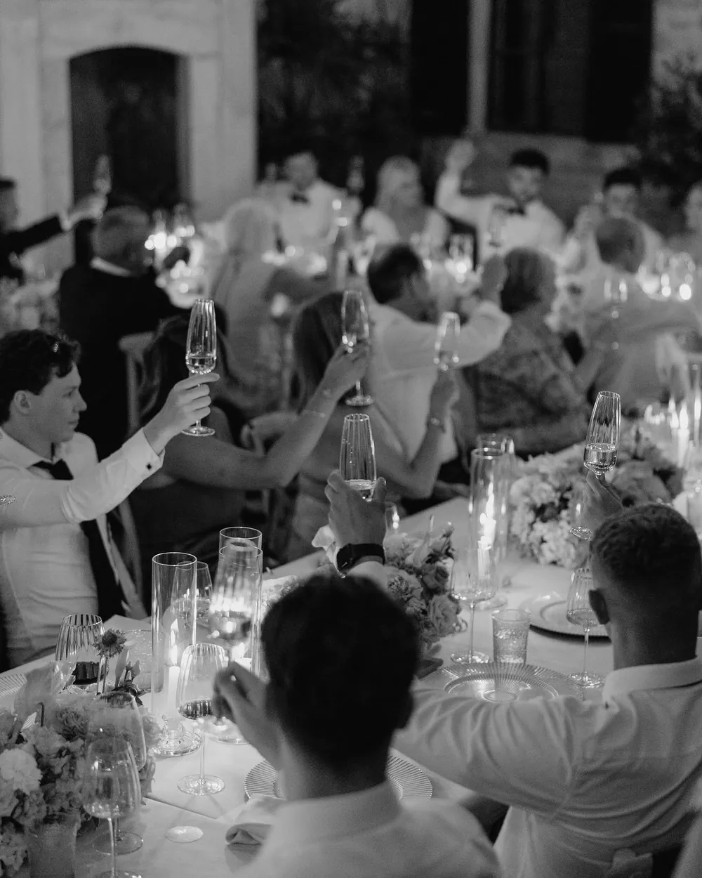 Guests raising glasses of cava at a candlelit wedding dinner