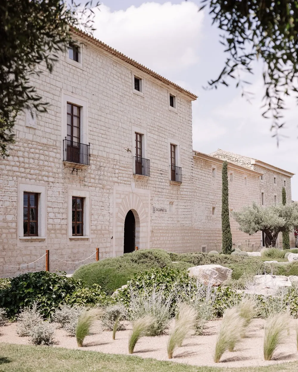 Stone façade of Finca Morneta in Binissalem, with olive trees and a Mediterranean garden