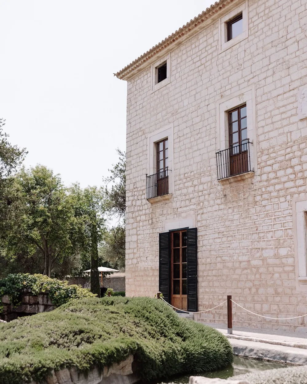 Side of the Finca Morneta house with green shutters, iron balconies and garden