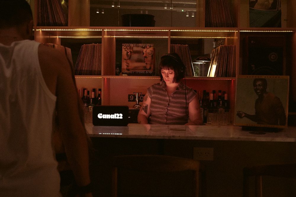 DJ con auriculares seleccionando vinilos detrás de la barra de discos en las Noches de Vinilos de Canal22