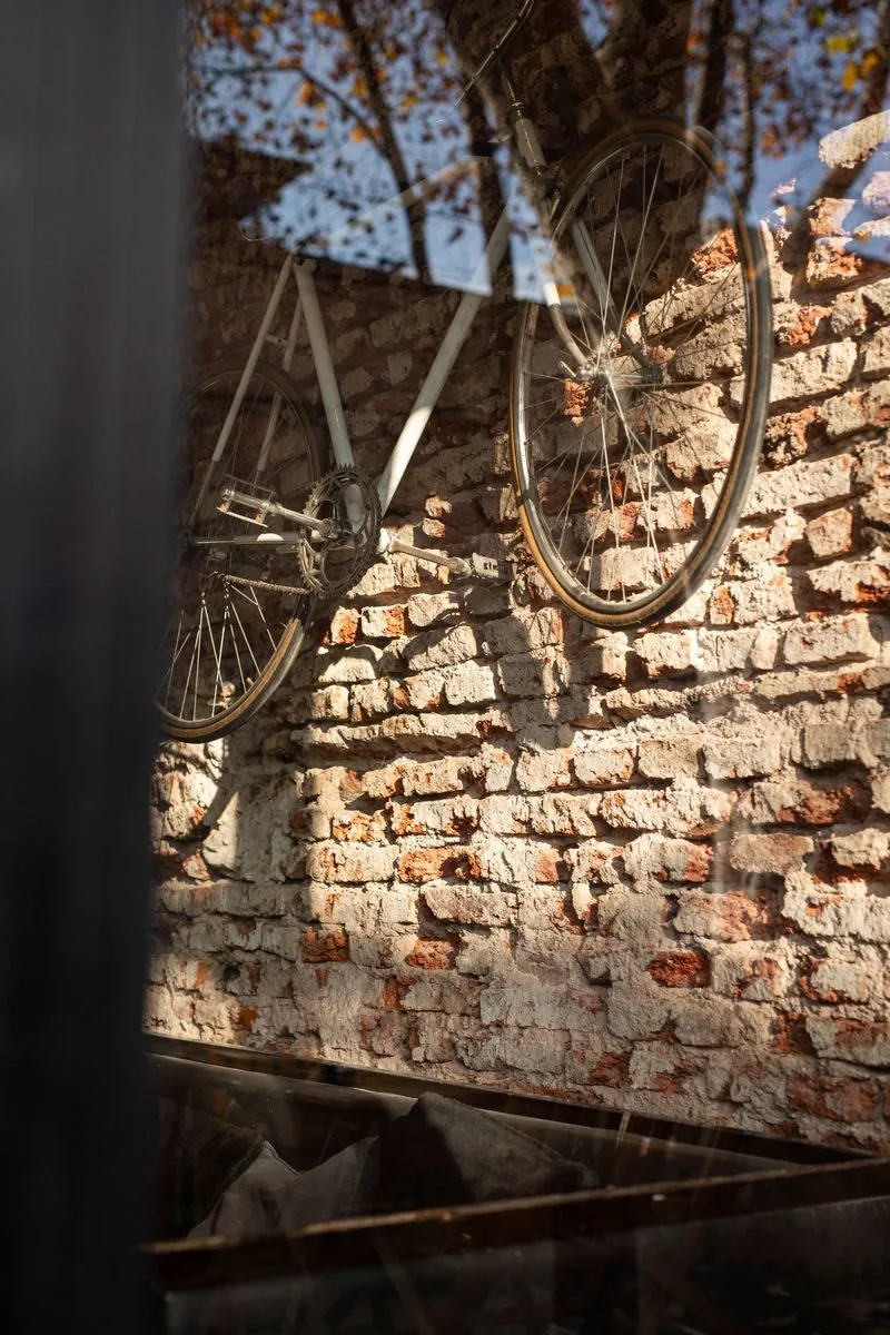 Bicicleta colgada en pared de ladrillo expuesto SĀNTAL Buenos Aires — detalle de interior con luz cálida