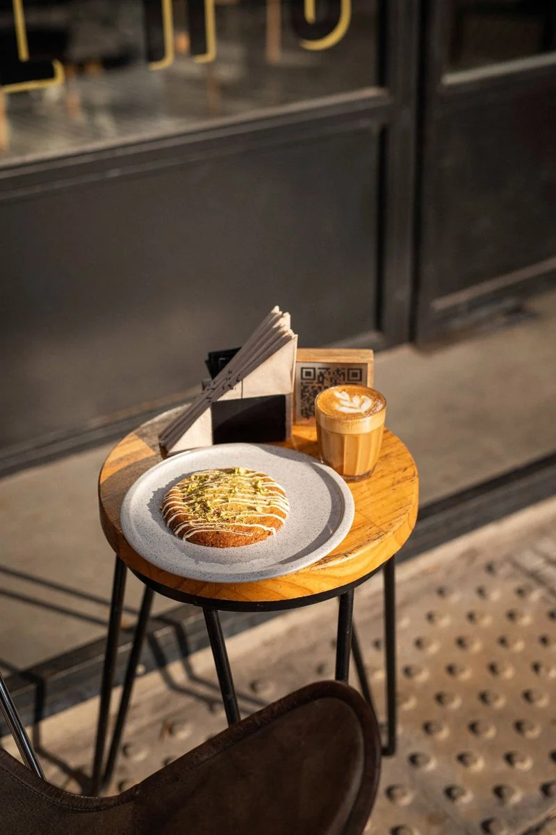 Mesa redonda al sol de la mañana con un café de especialidad y pastelería en SĀNTAL Buenos Aires, ideal para un brunch del Día de la Madre.